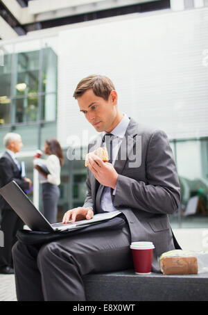 Businessman eat lunch and working outside office building Stock Photo