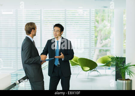 Businessmen talking in office building Stock Photo