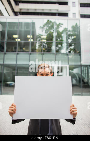 Businessman holding cardboard outside of office building Stock Photo