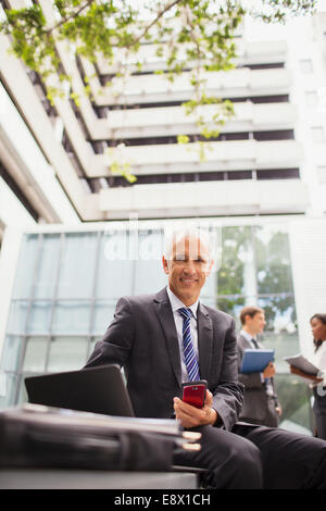 Businessman working on bench outside of office building Stock Photo