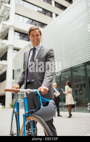 Businessman walking bicycle outside of office building Stock Photo