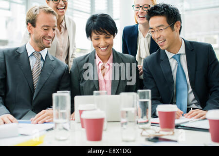 Business people gathered around laptop at table Stock Photo