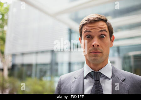 Businessman with eyebrows raised outside office building Stock Photo