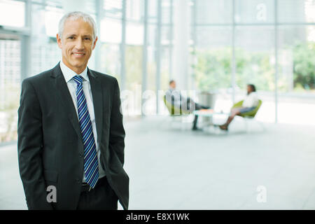 Businessman smiling in office building Stock Photo