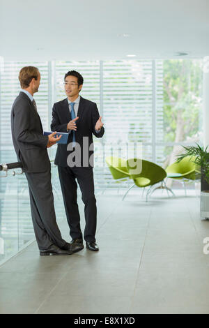 Businessmen talking in office building Stock Photo