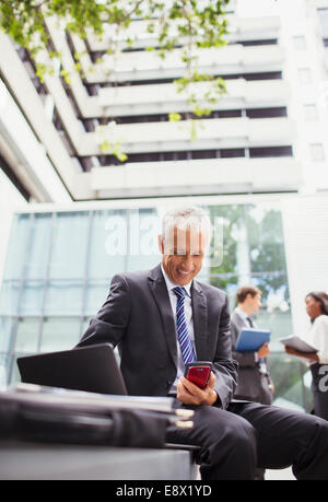 Businessman working on bench outside of office building Stock Photo