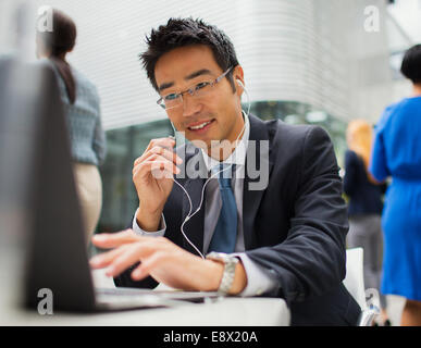 Businessman sitting at table talking on headset Stock Photo
