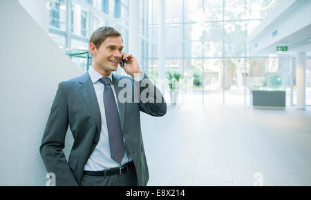 Businessman talking on cell phone in office building Stock Photo