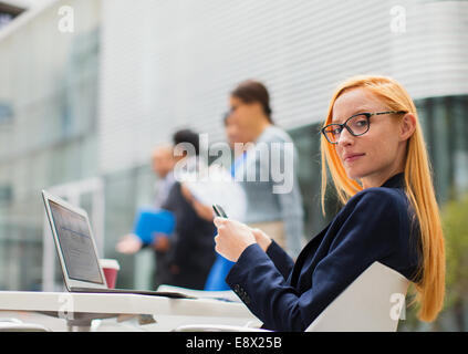 Businesswoman working at table outside of office building Stock Photo
