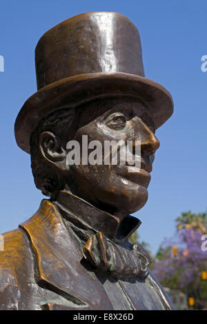 bronze statue of H C Andersen in top hat against a red brick wall ...