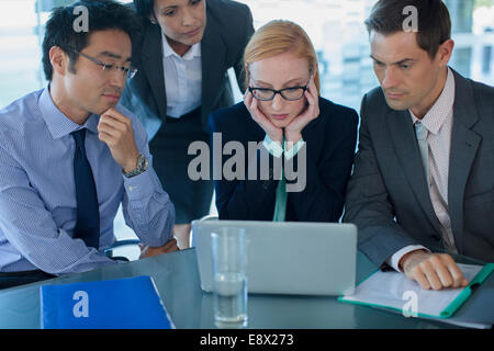 Business people gathered around laptop at table in office building Stock Photo