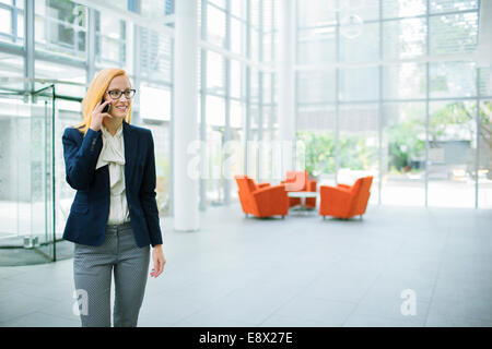 Businesswoman talking on cell phone in office building Stock Photo