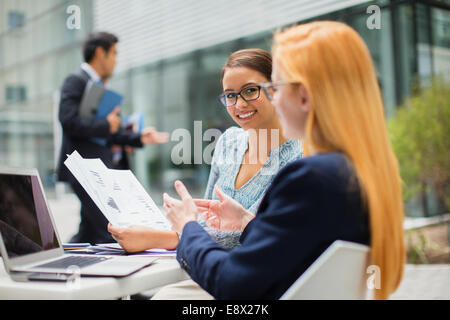 Businesswomen looking at documents at table in office building Stock Photo