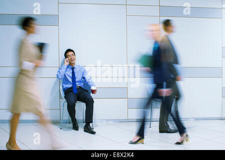 Businessman sitting talking on cell phone in office building Stock Photo