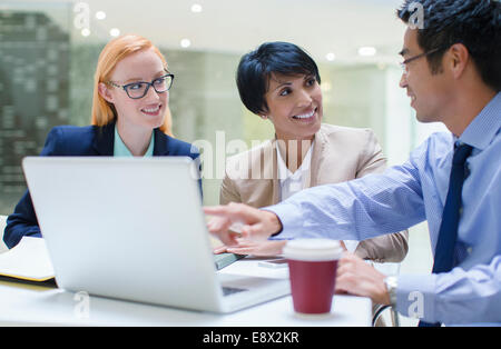 Business people gathered around laptop in office building cafe Stock Photo