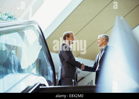 Businessmen shaking hands at top of stairs of office building Stock Photo