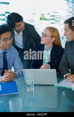 Business people gathered around laptop in office building Stock Photo