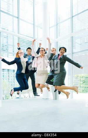 Business people jumping in office building Stock Photo