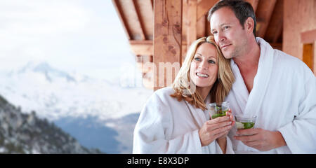 Couple in bathrobes standing on balcony together Stock Photo
