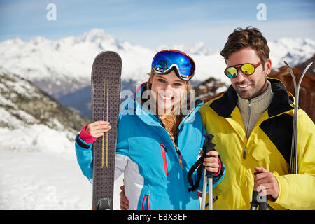 Couple carrying skis on mountain top Stock Photo