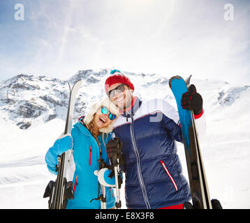 Couple carrying skis on mountain Stock Photo