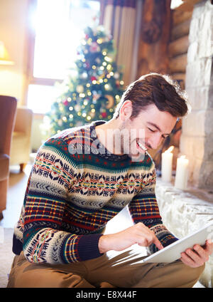 Man using digital tablet in log cabin Stock Photo