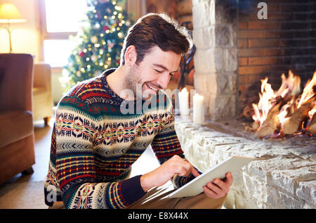 Man using digital tablet in front of fireplace Stock Photo