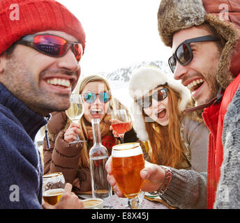 Friends celebrating with drinks in snow Stock Photo