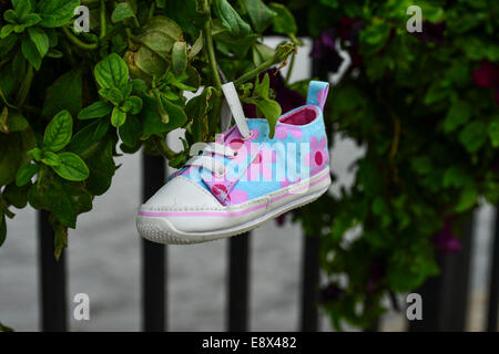 Stock Photo - Child's shoe hanging from outdoor plant display, Derry, Londonderry, Northern Ireland. ©George Sweeney /Alamy Stock Photo