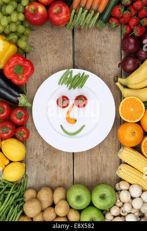 Smiling face from vegetables and fruits on plate with tomatoes, oranges and apples Stock Photo