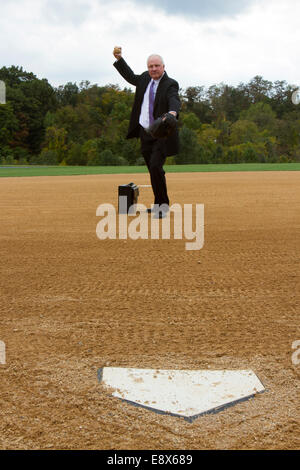 Businessman throwing a pitch on a baseball or softball playing field Stock Photo