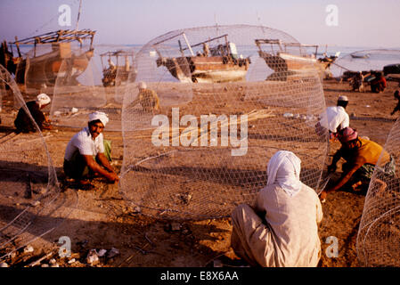 Migrant labour weaving wire fish-traps known as gandours, in Bahrain, 1974 Stock Photo
