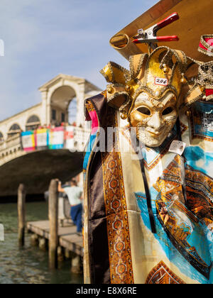 Venetian mask and sheet on sale at stand with Rialto Bridge in background. Stock Photo
