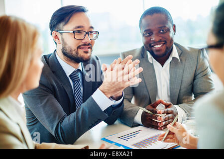 Happy Asian businessman looking at colleague during discussion Stock Photo