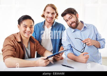Three happy young businessmen with document on clipboard Stock Photo
