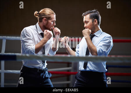 Businessmen fighting with one another on boxing ring Stock Photo