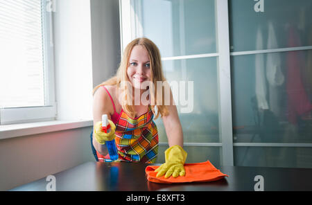 Happy girl cleaning table with furniture polish at home Stock Photo