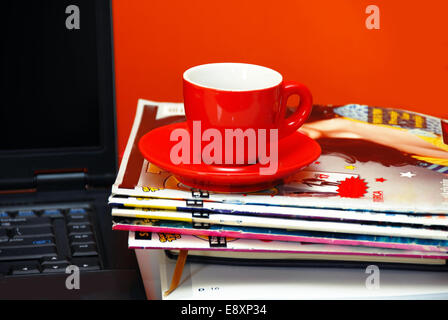 Red cup on magazines and notebook over red Stock Photo