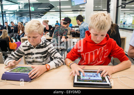 Boys playing games on their tablets, Schiphol Airport, Netherlands Stock Photo