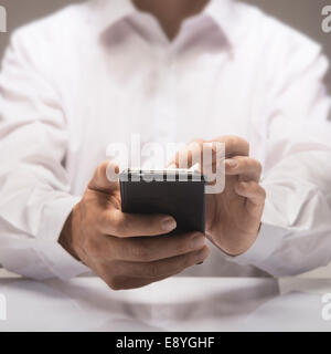 One smartphone in hands of a businessman wearing a white shirt Stock Photo