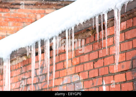 Icicles on a brick wall. Snowfall Stock Photo
