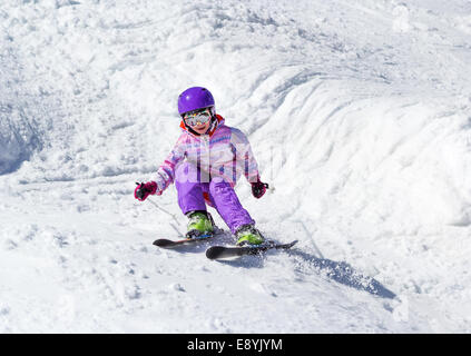 Little girl on skis in soft snow on a sunny day in the mountains Stock Photo