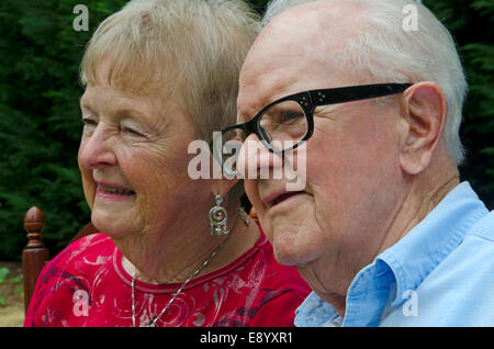 Close up portrait of an elderly couple. Subjects are smiling and looking away from the camera. Stock Photo