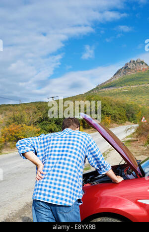 Adult man is standing near his broken car waiting for tow Stock Photo