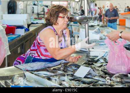 Portugal Olhao largest fishing port on Algarve Moorish town dates 1378 fish market mature lady serves customer pink plastic bag Stock Photo