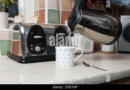 Premium Photo  Kettle pouring boiling water into a cup on grey background.  top view.