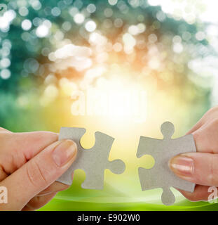 Fingers holding two puzzle pieces Stock Photo