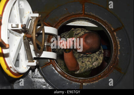 U.S. Navy Machinist's Mate 1st Class Ariel Ancheta climbs out of a hatch while conducting a tour of a U.S. Navy landing craft, utility assigned to Naval Beach Unit 7 for Philippine navy officers while aboard the amphibious assault ship USS Peleliu (LHA 5)