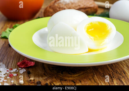 Two soft-boiled eggs in half on a plate, egg, parsley, spices and bread Stock Photo