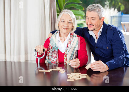 Grandmother Playing Dominoes With Grandson At Nursing Home Stock Photo